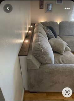 a couch sitting in the corner of a living room next to a wall with lights on it