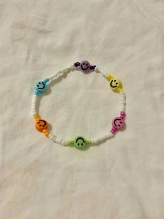 a bracelet with smiley faces on it sitting on top of a white cloth covered bed