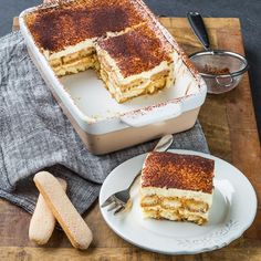 a cake sitting on top of a wooden cutting board next to a knife and fork