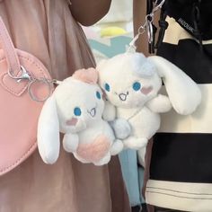 two white stuffed animals are attached to a pink purse