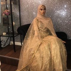 a mannequin dressed in gold sits on a black chair and looks at the camera