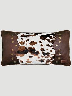 a brown and white cowhide pillow with gold studs