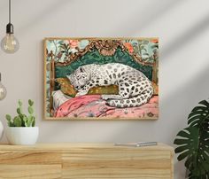 a large white leopard laying on top of a bed next to a potted plant