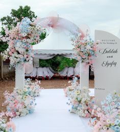 a wedding arch decorated with pink, blue and white flowers is set up for an outdoor ceremony