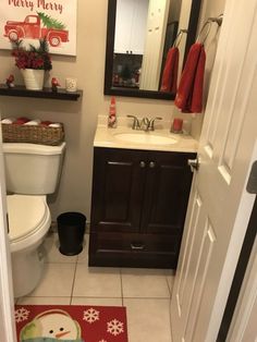 a bathroom with a toilet, sink and christmas decorations on the wall above it's mirror