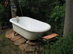 an old fashioned bathtub sitting in the grass next to a tree