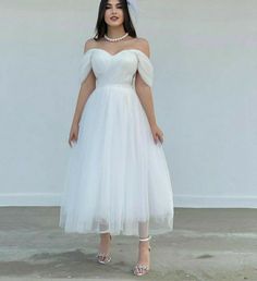 a woman wearing a white dress and headpiece is standing in front of a wall