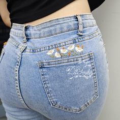 a woman's jeans with daisies embroidered on the bottom and side pockets