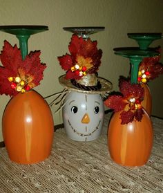 three pumpkins and two candlestick holders on a table