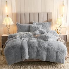 the bed is made up with fluffy blankets and pillows on top of it, along with two lamps