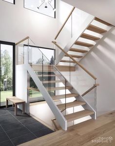 a stair case with glass railing and wooden handrails in a modern style home