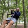 a man is swinging on a rope in the woods