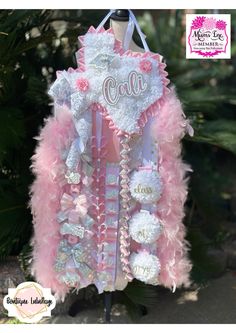 a pink and white jacket with the name colla on it, hanging from a tree