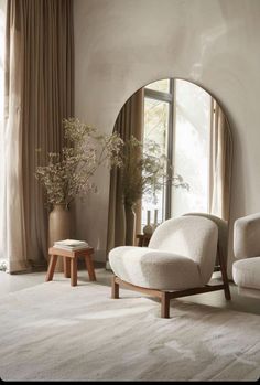 a living room filled with furniture and a large window covered in draping next to a white rug