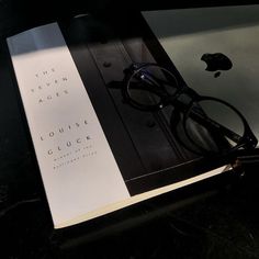 an open book sitting on top of a table next to a pair of eyeglasses