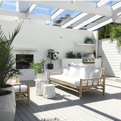 an outdoor living area with white furniture and potted plants