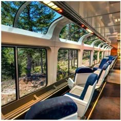 the inside of a train car with many seats and windows on each side, looking out at trees