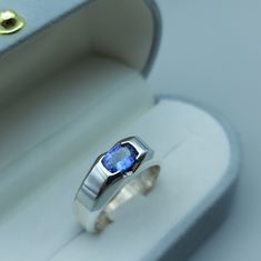 a ring with a blue stone sits in a box