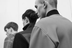 a group of men standing next to each other in front of a white wall with one man wearing a bald head