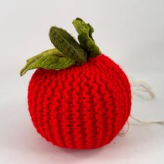 a knitted red apple sitting on top of a white table