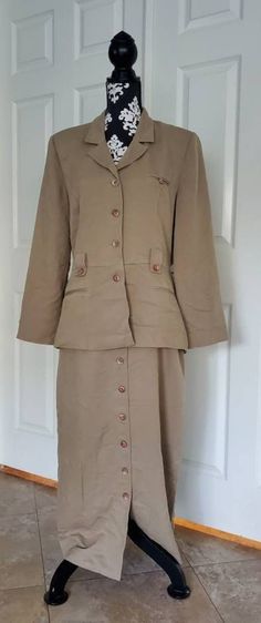 This unique one-piece suit from Jessica Howard gives the look of a matched blazer and skirt with the ease of wearing a dress.  The front of the blazer features a button closure and button accents at the belt loops and faux welt breastpocket.  There are two further faux welt pockets at the hip and shoulderpads for emphasized silhouette.  A notched collar at the neckline elevates the profile, while the elasticized waistband allows for all-day comfort.  The skirt front closes with the same buttons Fitted Office Lady Blazer With Buttons, Fitted Blazer With Buttons For Office Lady, Fitted Jacket Dress With Button Closure For Work, Fitted Jacket Dress With Notch Lapel, Fitted Jacket Dress With Notch Lapel And Buttons, Tailored Skirt Suit With Button Closure For Office, Fitted Skirt Suit With Button Closure For Work, Spring Workwear Skirt Suit With Buttons, Spring Skirt Suit For Workwear