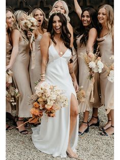 a group of women standing next to each other wearing dresses and holding bouquets in their hands