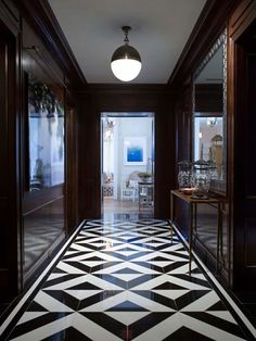 a hallway with black and white flooring next to a door leading to another room