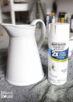 a white pitcher next to a spray bottle on top of a carpeted floor in a room