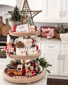 a three tiered tray with christmas decorations on it in the middle of a kitchen