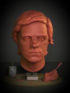 a clay bust of a man with glasses and a pencil in his hand on a table