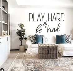 a living room filled with furniture and a large wall decal that says play hard be kind