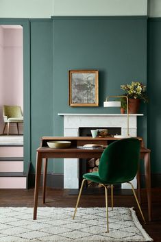 a dining room with green chairs and a white rug in front of the fireplace,