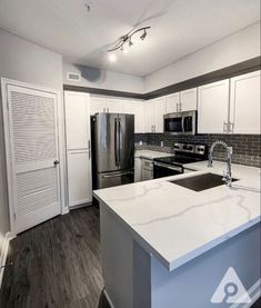 an empty kitchen with white cabinets and stainless steel appliances