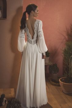 the back of a woman's white dress with long sleeves and lace on it