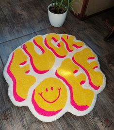 a smiley face rug is on the floor next to a potted plant