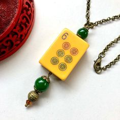 Vintage Bakelite Mahjong tile necklace with forest green jade beads.  Six dot tile.   Bronze Chain Length:  18, 20 24 inches  S H I P P I N G  The BLUE PEAR EMPORIUM is in Montreal, Canada.  Your purchase will be shipped by CANADA POST within 48 hours - exceptions are weekends and holidays. Your purchase will be wrapped in a kraft jewelry box with a ribbon and bow, ready for gifting.  Let us know if you would like a message on the enclosed card.   The shipping time estimates below will give you Green Beaded Rectangular Necklace, Green Rectangular Beaded Necklace, Vintage Green Rectangular Necklace, Handmade Green Rectangular Necklace, Green Rectangular Beaded Necklace Gift, Rectangular Green Beaded Necklace For Gift, Bohemian Green Rectangular Necklace, Unique Green Necklace With 108 Beads, Yellow Necklace With 108 Beads As Gift