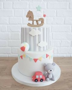 a white cake with an elephant and car decoration on the top, sitting on a wooden table