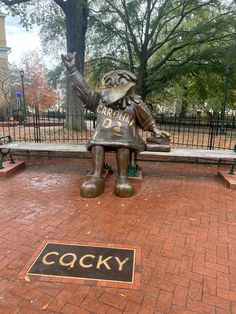 a statue of a man sitting on top of a bench in front of a park