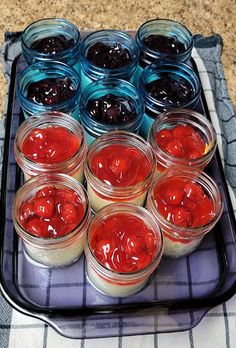 there are many jars with jams in them on the tray and next to each other