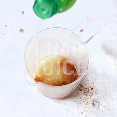 a plastic cup filled with something next to a green bottle