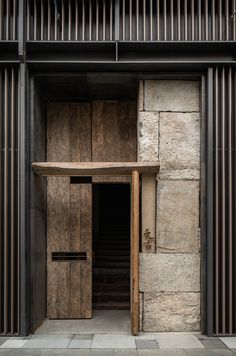 an entrance to a building with wooden slats on the outside and stone walls around it