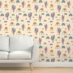 a white couch sitting in front of a wall with cactus and rainbows on it