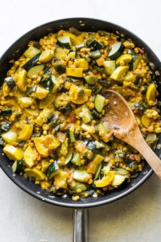 a skillet filled with corn and zucchini on top of a white counter