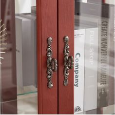 an image of a red door handle on the side of a book case with books behind it