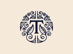 the letter t is surrounded by leaves and swirls in this monogrammed logo