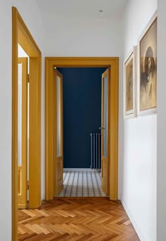 an empty hallway with yellow doors and pictures on the wall in front of it's doorway