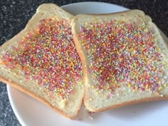 two pieces of bread with sprinkles on them sitting on a white plate