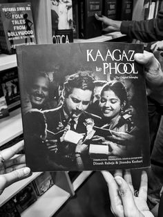 two hands holding up a book in front of a group of people at a bookstore