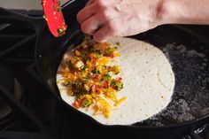 a person cooking food in a skillet on the stove