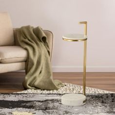 a living room with a chair, rug and a gold stand on the floor in front of a couch